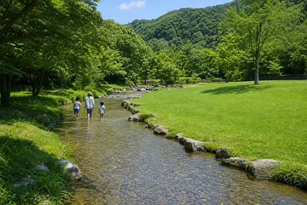 大野城いこいの森 水辺公園の浅いせせらぎと芝生で家族が水遊びをする様子