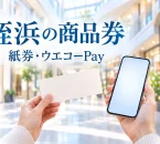 姪浜の紙商品券とウエコーPayを紹介するイメージ。買い物の手元と、文字「姪浜の商品券」「紙券・ウエコーPay」